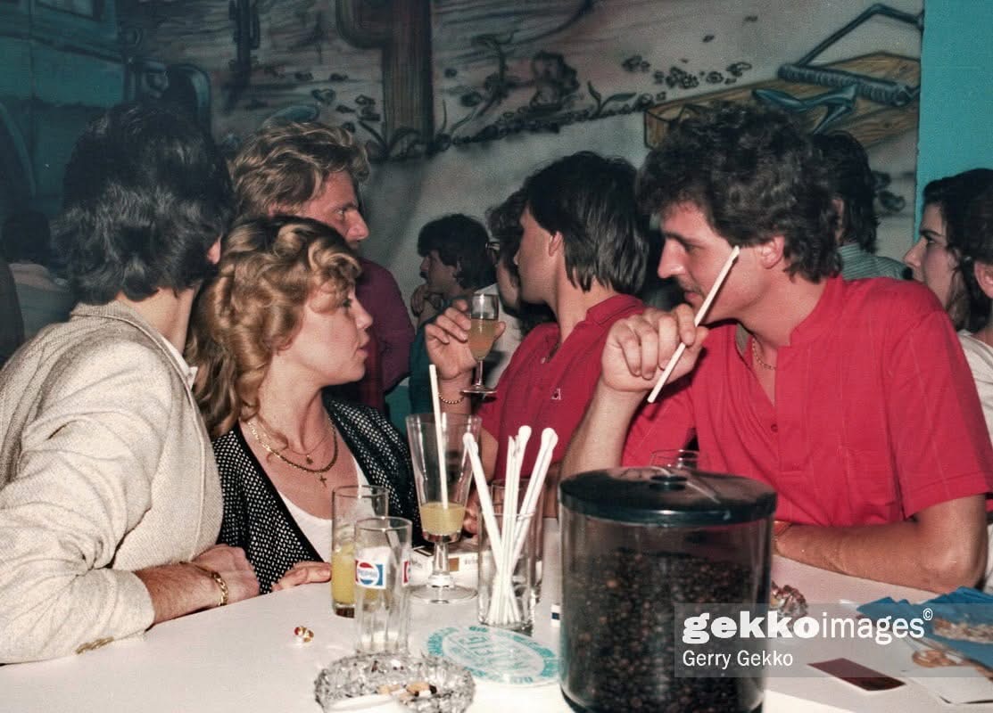 Vintage Cage, 1980er Jahre — Gäste am Tisch vor dem Wandbild